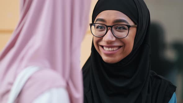 Close-up view of a happy arabian women wearing national hijab is talking to her friend