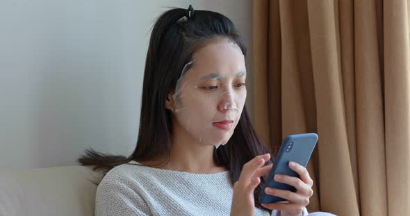 Woman use paper mask with cellphone at home