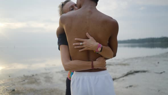 Interracial Couple with Age Differences Embrace and Kissing on Beach at Sunset Push Back Slow Motion