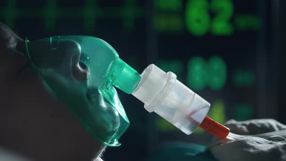 A Female Patient in Medical Mask is Breathing Oxygen Support in a Hospital Next to Heart Rate