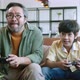 asian dad son play video game together at home fun and excited hand hold joystick - VideoHive Item for Sale