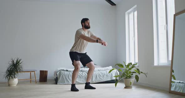 Young Bearded Man Doing Squats Exercises at Home