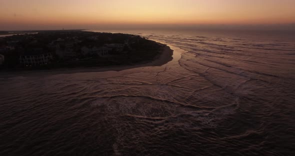 Aerial of ocean waves on island beach at sunrise