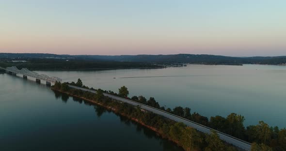 Aerial view of the vastness of a large lake then panning towards a bridge and highway across the lak