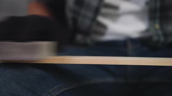 Black Guy in Working Gloves Polishes Wooden Plank in Shop