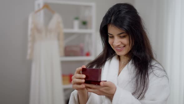 Portrait of Excited Smiling Middle Eastern Bride Admiring Wedding Rings in Box Dreaming