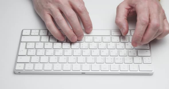 The Person is Typing on a Computer Keyboard of White Color Closeup View Soft Light Bluetooth Device