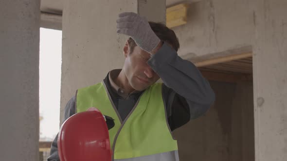 Tired Man Taking off Hard Hat