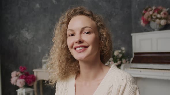 One Person 30s Young Caucasian Curly Blond Woman Looking Into the Camera and Smiling with Flowers on