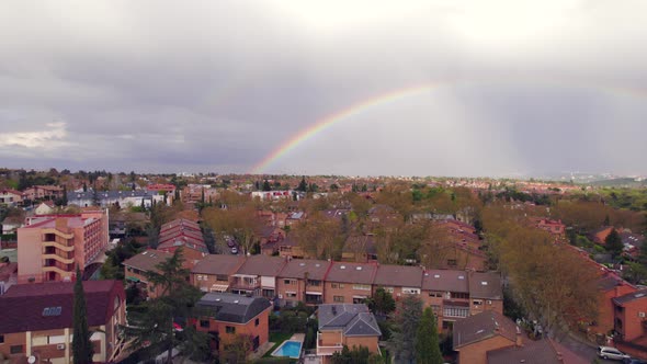 Colorful rainbow in the sky over residential Spanish neighborhood. Aerial view