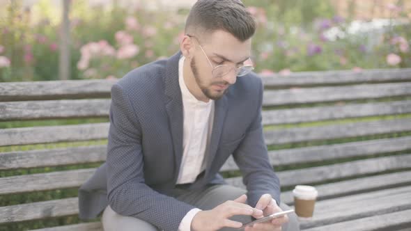 Portrait of Young Businessman Sitting on a Bench Outdoors