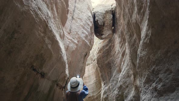 Woman Walking Among High Rocks and Taking Pictures on Mobile