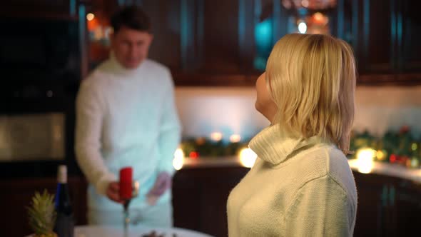 Charming Plussize Adult Woman Looking Back at Blurred Man Setting Table with Romantic Dinner Turning