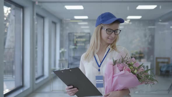 Young Smiling Girl with Glasses and Cap Works in Delivery Service, Female Employee Delivers Bouquet