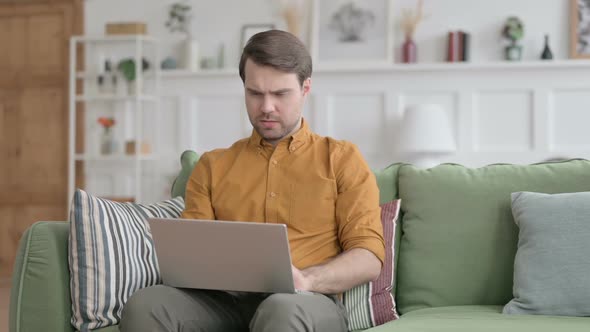 Young Man Shaking Head as Yes Sign while using Laptop in Office