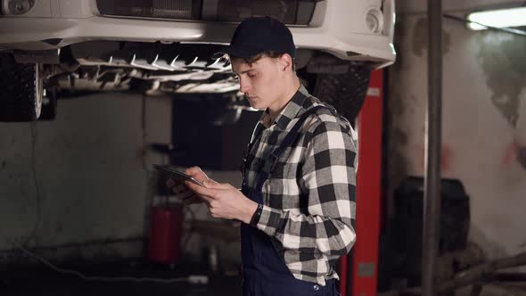 Mechanic in Auto Repair Service Center Using Digital Tablet