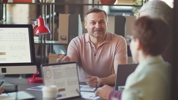 Middle Aged Businessman Holding Team Meeting in Office