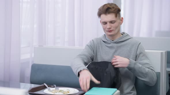 Young Handsome Smart Student Packing Backpack and Leaving Cafeteria