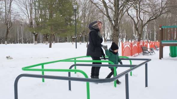 Son with Mom Pass the Snake on the Playground