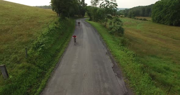 Aerial views of family bicycling along pastoral country roads.