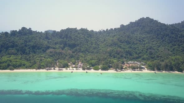 Aerial view of beautiful island with accommodation by the beach in Thailand - camera backwards track