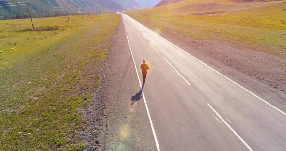 Low Altitude Flight in Front of Sporty Man at Perfect Asphalt Road