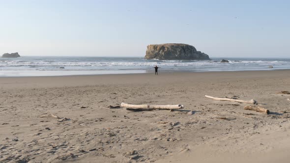 Long haired man spins on the golden sand beach of Oregon