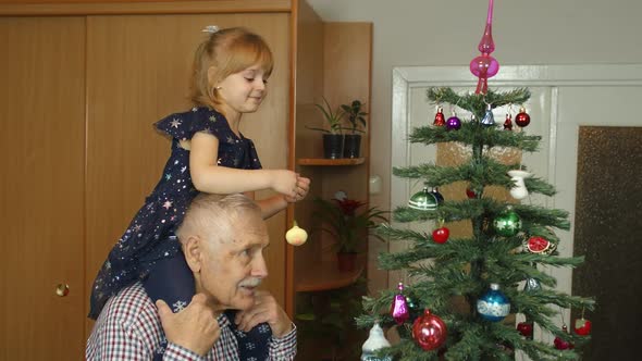 Children Girl and Elderly Grandpa Decorating Artificial Christmas Pine Tree at Oldfashion Room Home