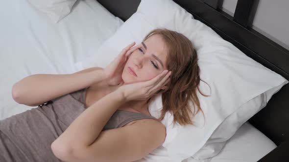 Woman Lying in Bed with Headache Pain in Head