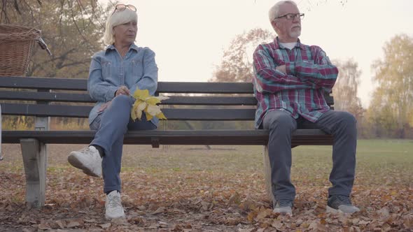 Upset Senior European Couple Sitting on the Bench Separately. Mature Caucasian Family Quarrelled