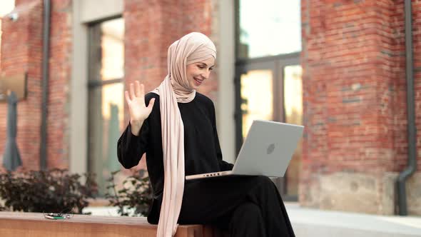 Portrait of Smiling Happy Muslim Woman Relaxing Using Digital Laptop While Sitting on Bench