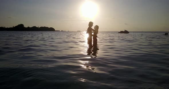 Fun boy and girl on romantic honeymoon enjoy life on beach on sunny white sandy background 