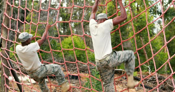 Military Soldier Climbing Rope During Obstacle Course alt