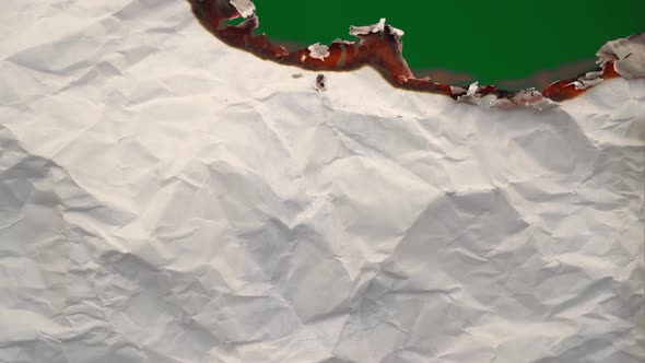 White Paper Burns From Above on a Green Background Copy Space