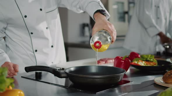 Male Chef Pouring Sunflower Oil From Bottle in Pan on Stove