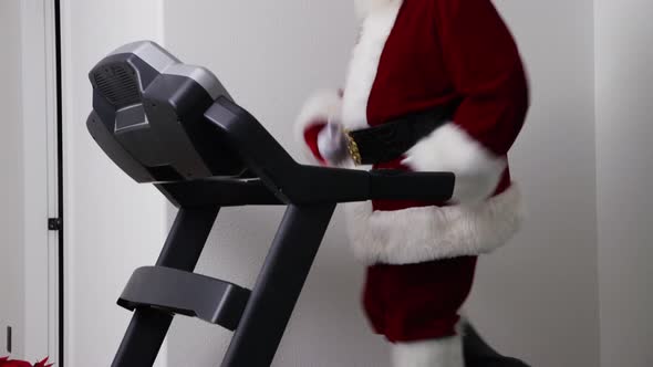 Santa Claus running on treadmill in gym alt