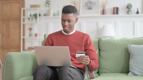 African Man with Unsuccessful Online Payment on Laptop on Sofa