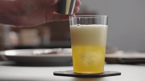 Slow Motion Man Pour Aperitivo in Orange Soda with Ice in Tumbler Glass to Make Spritz Drink on