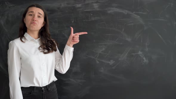 Caucasian Student Girl Stands Near the Chalk Board Raises Her Index Finger and Points to an Empty