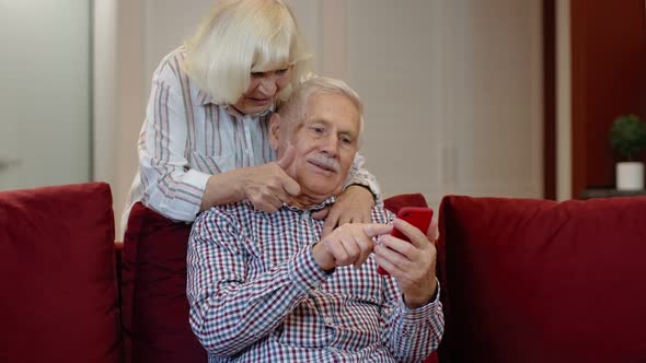 Senior Old Couple Grandparents Talking and Using Mobile Phone Computer at Home. Internet Shopping