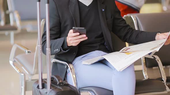 Closeup Smartphone in Male Hands and Newspaper Inside in Airport. Casual Young Businessman Wearing