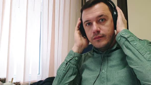 Man puts on headphones, listens to interlocutor and nods his head