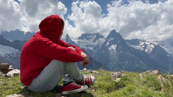 Adult Male in Red Hoodie with Hood Enjoying Beautiful View in Mountainous Area