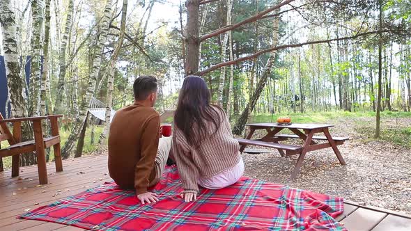 Young Couple Sitting on the Terracein the Autumn Forest