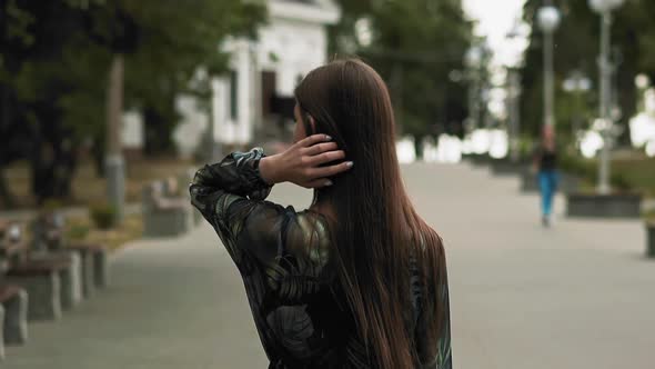 Woman with Long Loose Hair Walks on City Promenade Back View