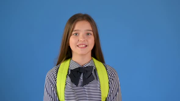 Portrait of a happy teenage girl in a school uniform with a backpack smiling