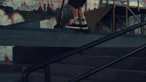 Young Scooter Rider Performing Jump Trick on Ramp at Urban Skate Park