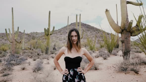 Slow Motion Camera Zooms in on Beautiful Young Woman Posing with Challenging Look at Amazing Cactus