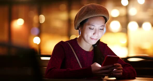 Woman use of mobile phone at outdoor coffee shop at night