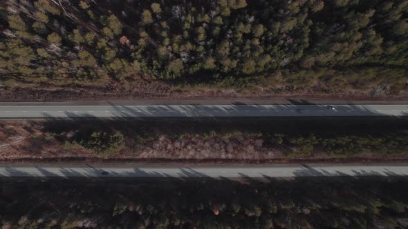 Traffic cars on multiple lane highway road between deep forest